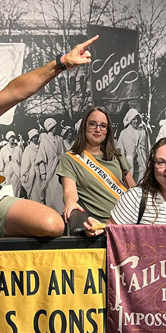 Three people at a womens' sufferage exhibit