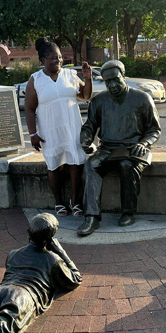 Black woman in a white dress surrounded by statues