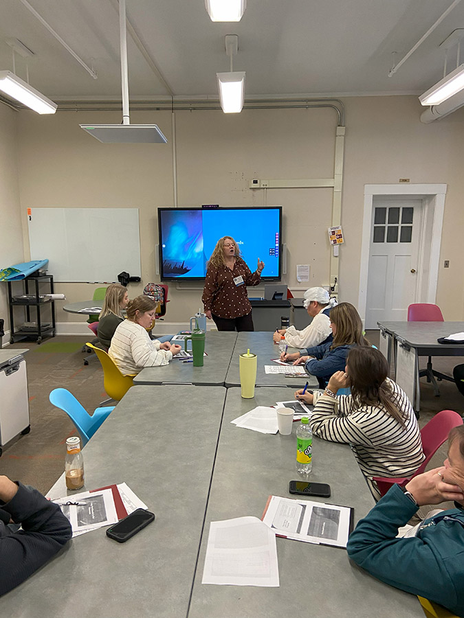 Jennifer Gribben presenting about storyboards at the end of a conference table