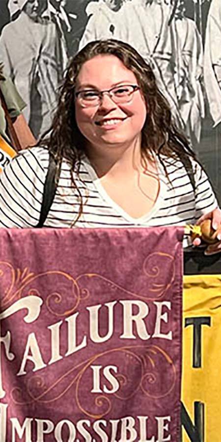 Woman standing behind a banner which reads 