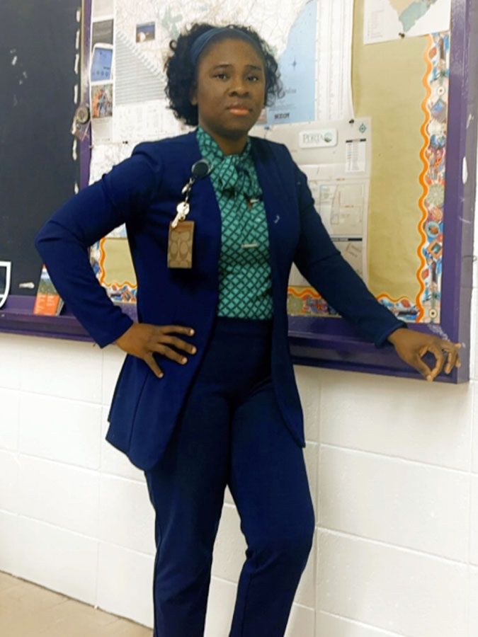 Black woman posing next to a bulletin board.