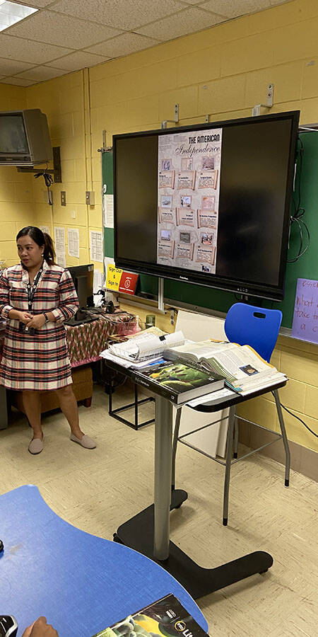 Woman in a plaid dress in a classroom.