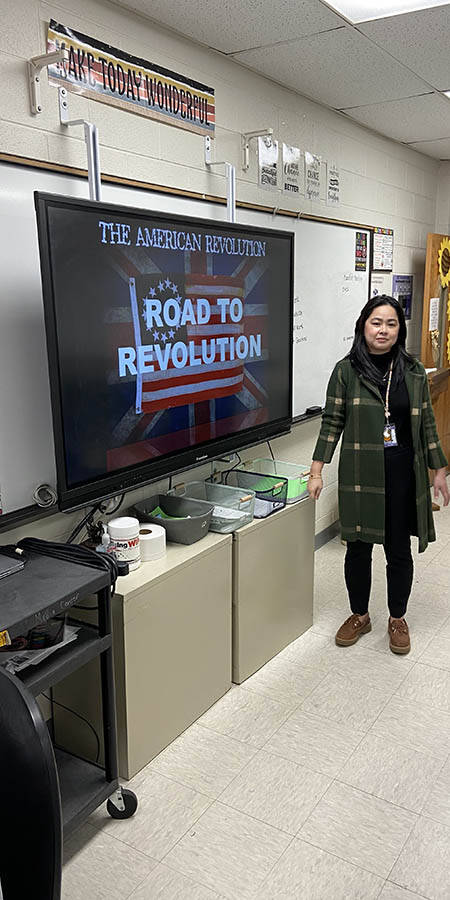 Teacher standing in front of a screen that reads