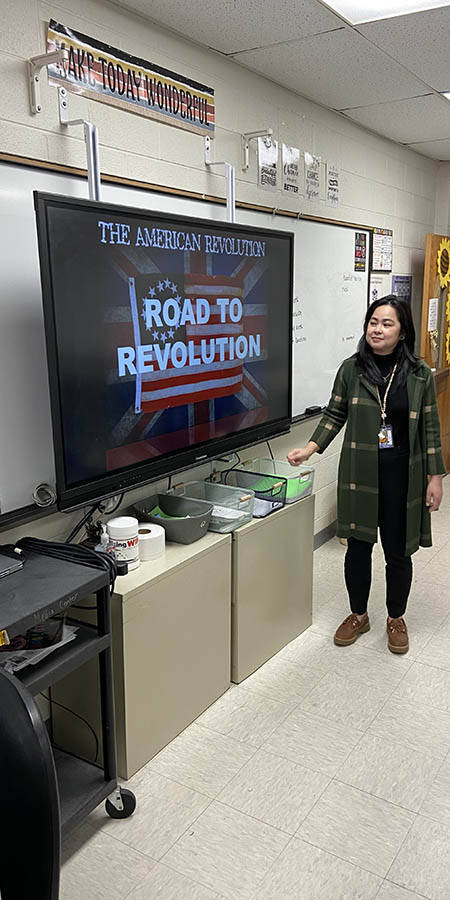 Teacher standing in front of a screen.