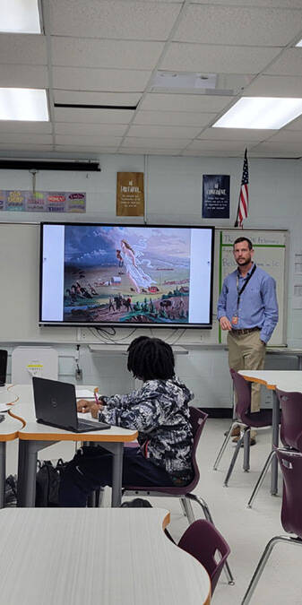 Teacher at a screen in the front of a classroom.