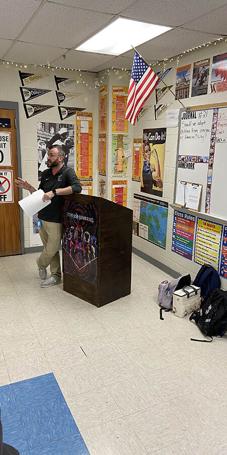 Teacher leaning on a podium.