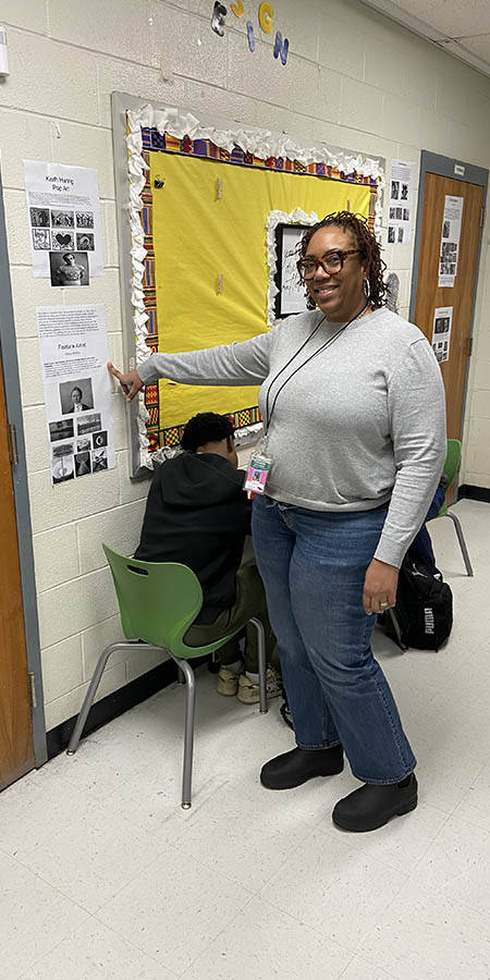 Teacher pointing at papers on a wall.
