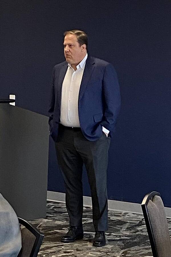 Man in a dark suit jacket standing near a podium.