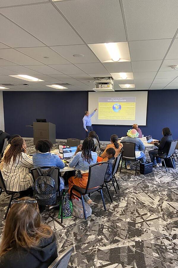 Man in a blue shirt leading a discussion with a slideshow.