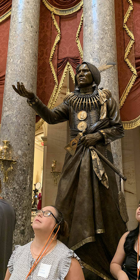 women looking up. a bronze statue is in the background.