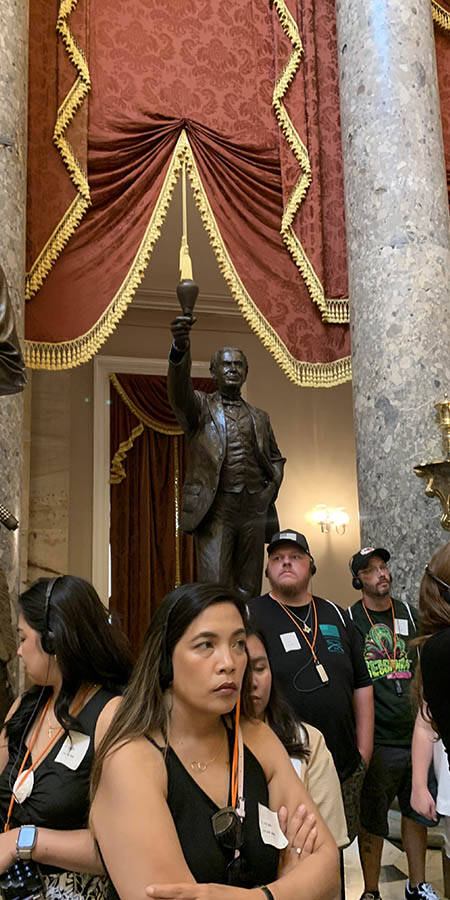 Woman with folded arms in a crowded room with statues in the background.