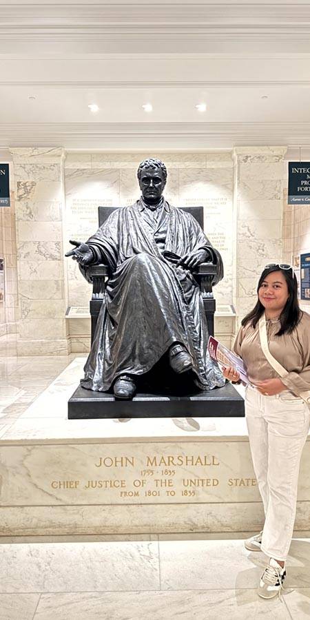 Woman standing next to a statue.