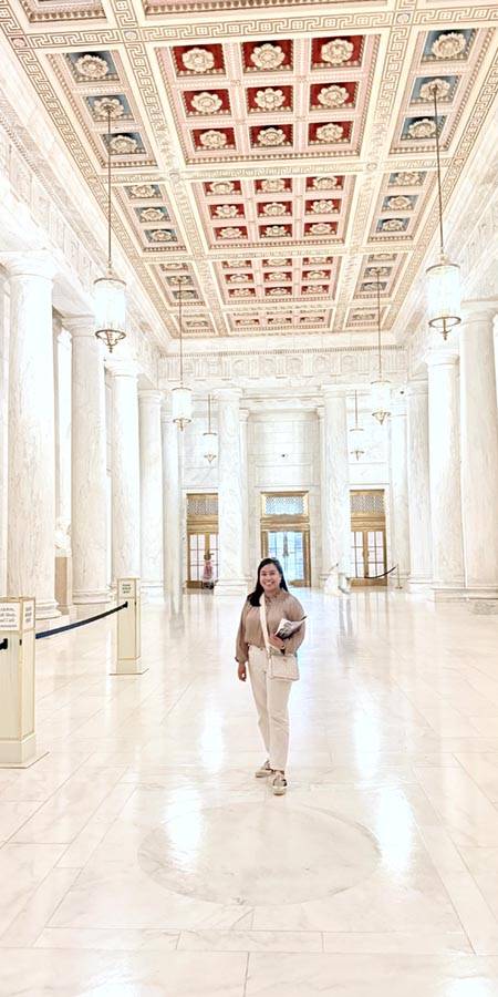Woman in a room of marble columns.