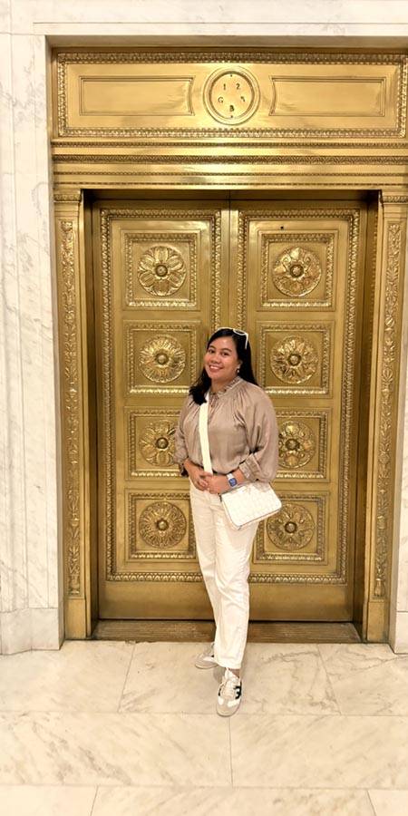 Woman standing in front of a gold door.