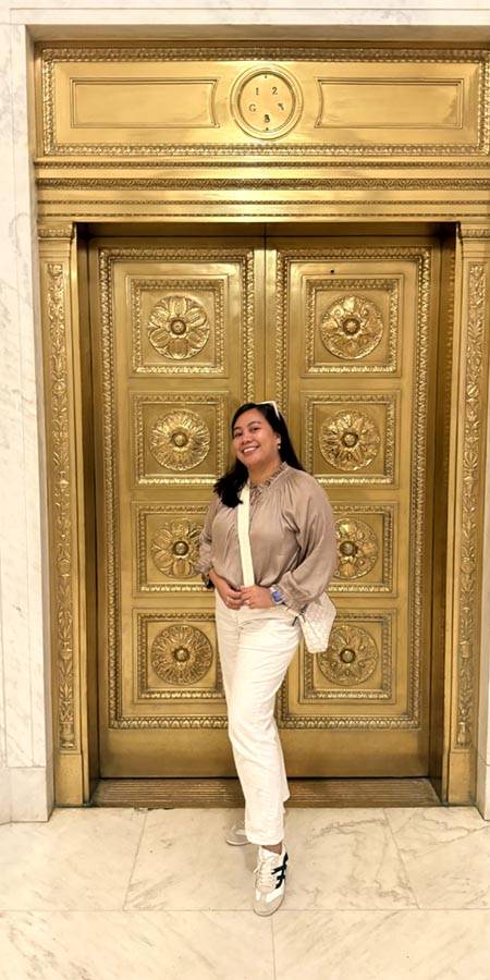 Woman standing in front of a gold door.