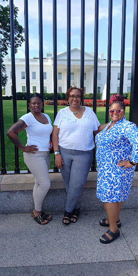 Three black women outside the gates to the White House.
